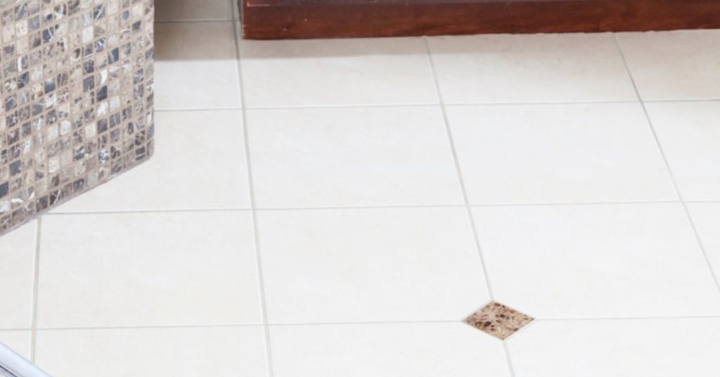 Close-up of a tiled floor with freshly applied grout colorant, showcasing a seamless and vibrant finish